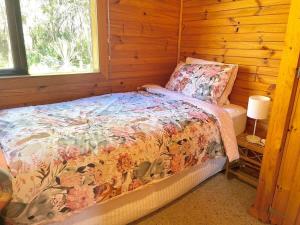 a bedroom with a bed in a wooden cabin at Rosemary Cottage - short walk to Gannet Beach in Bawley Point