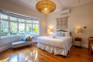 a bedroom with a bed and a chair and windows at Island Villa- Stay Waiheke in Oneroa