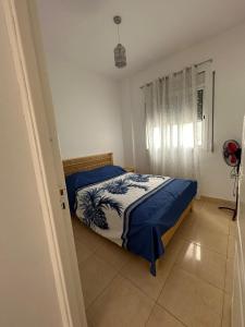 a bedroom with a bed with a blue and white comforter at Appartement des vacances à Bades près de corniche in Al Hoceïma
