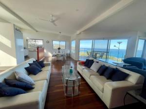 a living room with two couches and a table at Stunning Ocean Views - overlooking Merry Beach in Kioloa