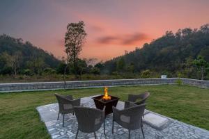 a fire pit in the middle of a lawn with chairs at SaffronStays Sukh Saklana Haveli Royalty Rooms - Forest-view stay with pool, expansive lawns & dining near Rishikesh and Dehradun Airport in Dehradun