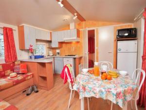 a kitchen with a table with fruit on it at Mobil home 6 pers avec terrasse - API-1-52-172 in Meyrueis
