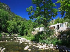 a house on a hill next to a river at Mobil home 6 pers avec terrasse - API-1-52-172 in Meyrueis