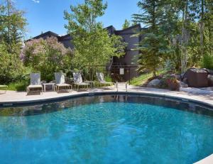 a swimming pool with chairs and a house at Latitude Loft Aspenwood #K20 Studio1B in Snowmass Village