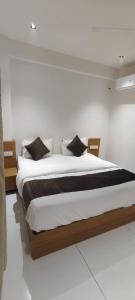 a bedroom with a large bed with black pillows at Hotel Pine View in Rajkot