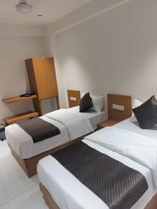 two beds in a room with white walls at Hotel Pine View in Rajkot +72 photos