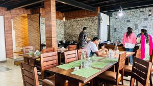 un grupo de personas sentadas en una mesa en un restaurante en Ibex Resorts, Valparai Tale Rock, en Vālpārai