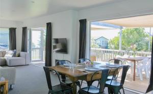 a living room with a table and chairs and a balcony at Coastal Retreat - Whiritoa Holiday House in Whiritoa