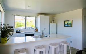 a kitchen with a sink and a counter with stools at Coastal Retreat - Whiritoa Holiday House in Whiritoa