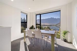 una sala da pranzo con tavolo e sedie e una grande finestra di Frankton Retreat Modern 3BR with Lake Views a Queenstown