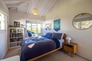 a bedroom with a bed and a book shelf at Palm Beach Retreat - Be My Guest Waiheke in Waiheke Island +28 photos