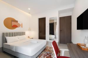 ein Schlafzimmer mit einem weißen Bett und einem roten Stuhl in der Unterkunft Cove Dra House in Jakarta