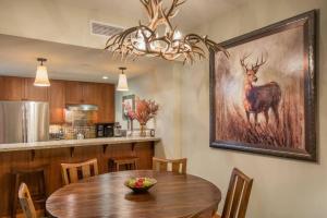 a dining room with a table and a painting of a deer at The Powder Den Cozy Alpine Basecamp in Snowmass Village