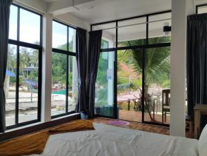 Un dormitorio con una cama y grandes ventanales. en Waterfall Guesthouse1, en Phumĭ Kaôh Rŏng