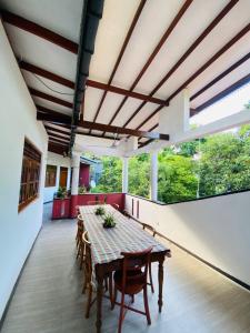 a dining room with a table and chairs and windows at Heaven Of Hikka in Hikkaduwa