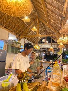 a man and a woman preparing food in a kitchen at Pantai Hans Villas in Gili Air