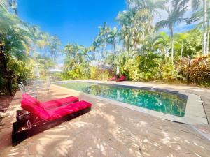 een zwembad met een rode bank naast een resort bij The Villas Palm Cove in Palm Cove