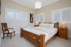 a bedroom with a large bed and a chair at Claremont - Timeless Foreshore Retreat by the Wharf in Stockton