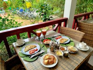 a table with breakfast food and drinks on a balcony at Lucy's guesthouse in La Digue