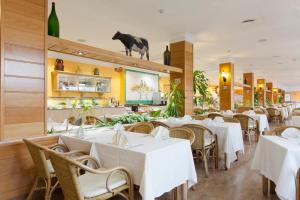 a restaurant with white tables and chairs and a cow on the wall at Mirador del Cabo Designed For Adults in Aguadulce