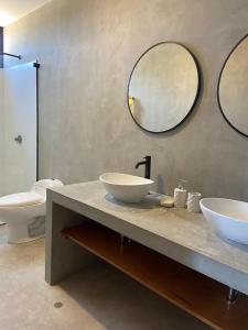a bathroom with two sinks and a toilet and two mirrors at La Morada - Casa de playa frente al mar en Estreno in Canoas De Punta Sal