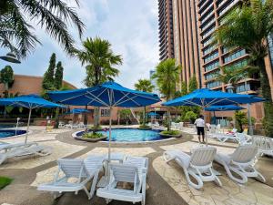 a pool with blue umbrellas and white chairs at Luxy Service Apartment at Times Square KL in Kuala Lumpur