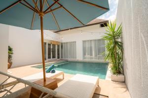 a pool with a blue umbrella and a swimming pool at Villa Palma Blanca Canggu by Nagisa Bali in Canggu