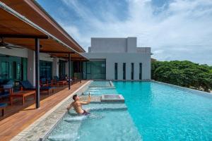 a man in a swimming pool next to a house at The Cavalli Casa Resort in Phra Nakhon Si Ayutthaya