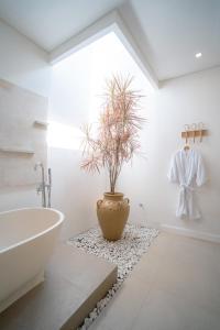 a bathroom with a tub and a potted plant at Villa Palma Blanca Canggu by Nagisa Bali in Canggu +24 photos