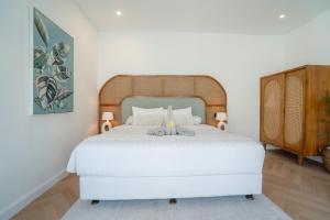 a bedroom with a white bed with a wooden headboard at Villa Palma Blanca Canggu by Nagisa Bali in Canggu