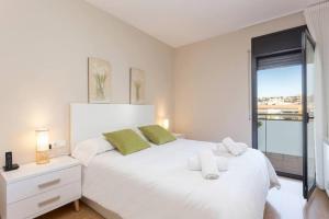 a white bedroom with a large white bed and a window at New Apartment With Private Rooftop in Hospitalet de Llobregat