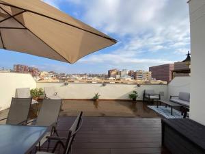 a rooftop patio with chairs and an umbrella at New Apartment With Private Rooftop in Hospitalet de Llobregat
