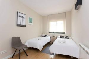 a room with two beds and a chair and a window at New Apartment With Private Rooftop in Hospitalet de Llobregat +17 photos
