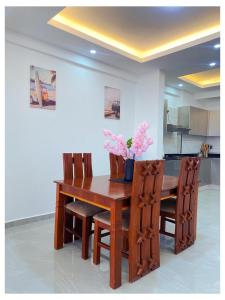 a wooden dining room table and chairs with flowers on it at Sakura Aqua Gardens in Mombasa