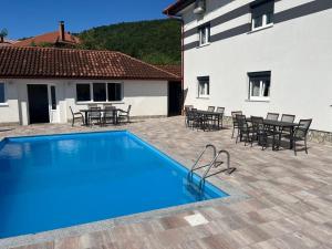a swimming pool in front of a house with tables and chairs at Althea Home & Wellness in Bihać