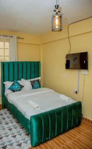 ein Bett mit einem grünen Kopfteil in einem Zimmer in der Unterkunft Verdant Cozy Studio with WI-FI in Nanyuki