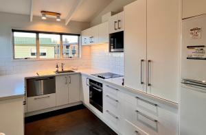 een witte keuken met witte kasten en een raam bij Sunnyview - Lake Tekapo in Lake Tekapo