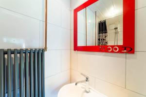 bagno con specchio rosso e lavandino di Studio Wolken, Wind en Water. a Petten