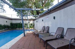 a group of chairs sitting next to a swimming pool at Cozy Villa Morra Apt in Asunción