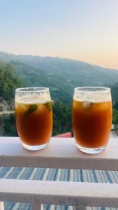two glasses of tea sitting on a ledge with a view at Rosewood Cottage in Mukteshwar