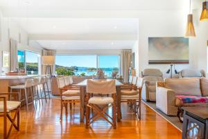 a dining room and living room with a table and chairs at Shelley Beach Homestead in Waiheke Island