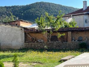 a house with a stone wall next to a mountain at Къща Христини in Kalofer