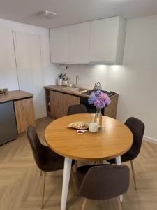 a kitchen with a wooden table with chairs and a vase of flowers at Apartament u Moni in Krajno Pierwsze