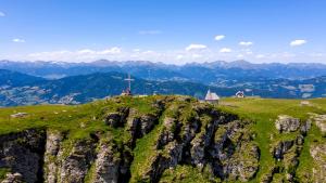 a hill with a cross on top of a mountain at Almdorf Stadl by ALPS RESORTS in Stadl an der Mur