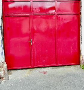 a red metal garage door on a building at Casa Ming in Braşov