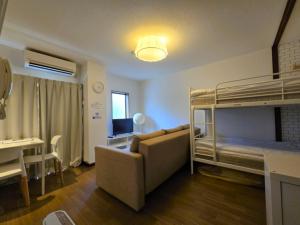 a living room with a couch and bunk beds at Comfort CUBE PHOENIX Beppu (やよいビル) in Beppu