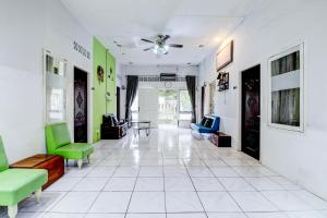 einen Flur mit grünen und weißen Stühlen und einem Tisch in der Unterkunft Dancenter Nelvi Guesthouse in Padang