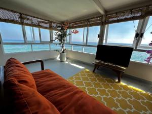 a living room with a couch and a table with a laptop at Beach front villa , All Mare 2 in Uluwatu +48 photos