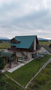 a large building with a green roof on a field at Vila Tea Durmitor in Žabljak