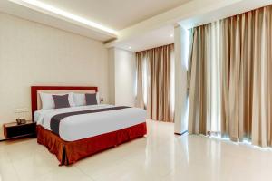 a bedroom with a bed and a large window at OYO 94723 Premium Legian Hotel in Legian